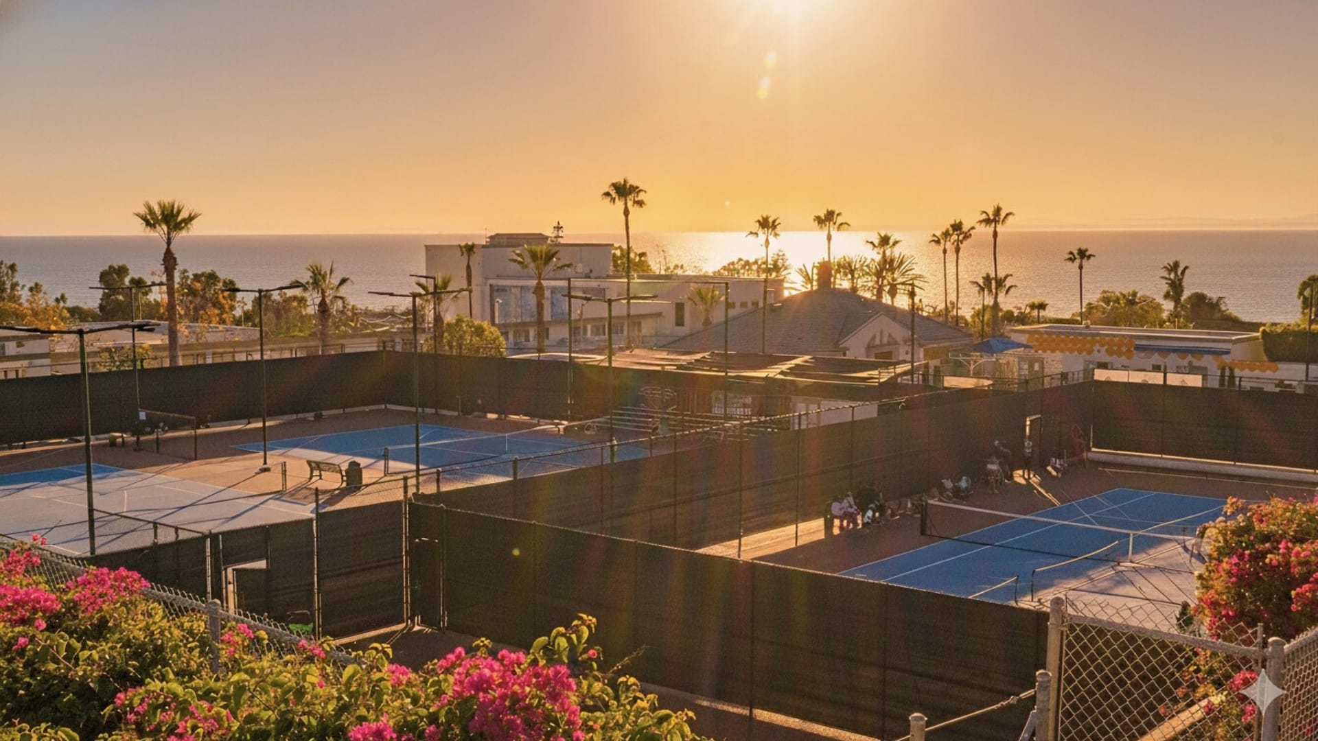 Coastal tennis facility at sunset — blue courts and ocean horizon