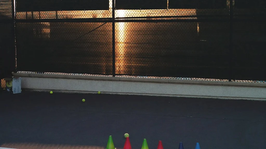 Tennis court at dusk with warm light through the fence at LBTA