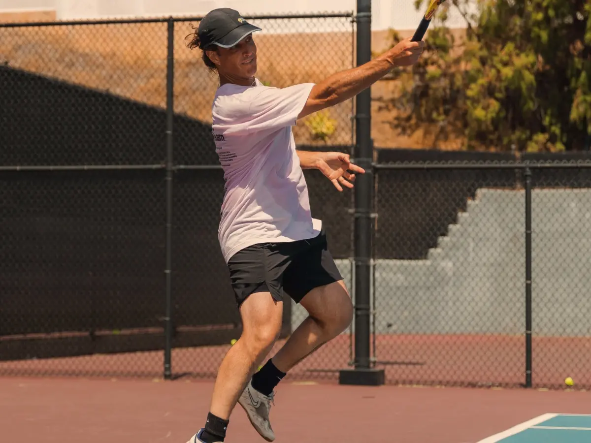 Advanced adult players practicing doubles strategy under late-day sunlight