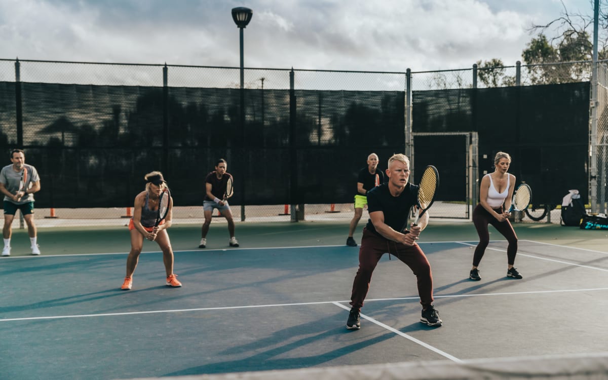 Adults in ready position across a full court under the lights