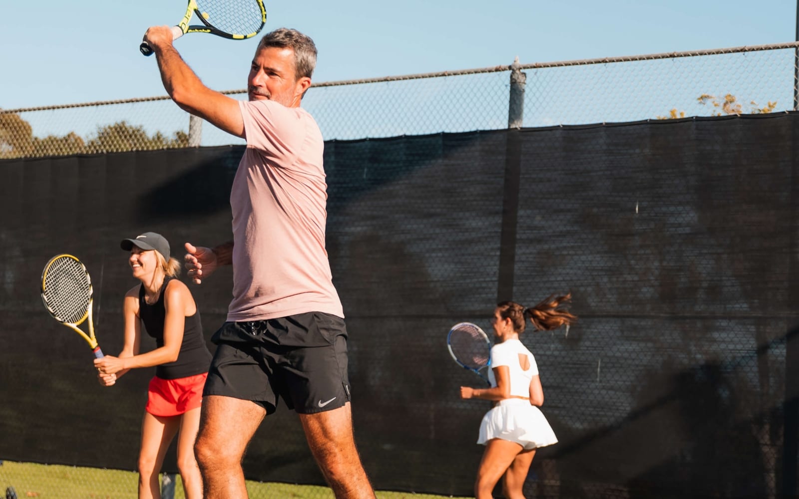 Adults training together on court in the morning, mid-swing