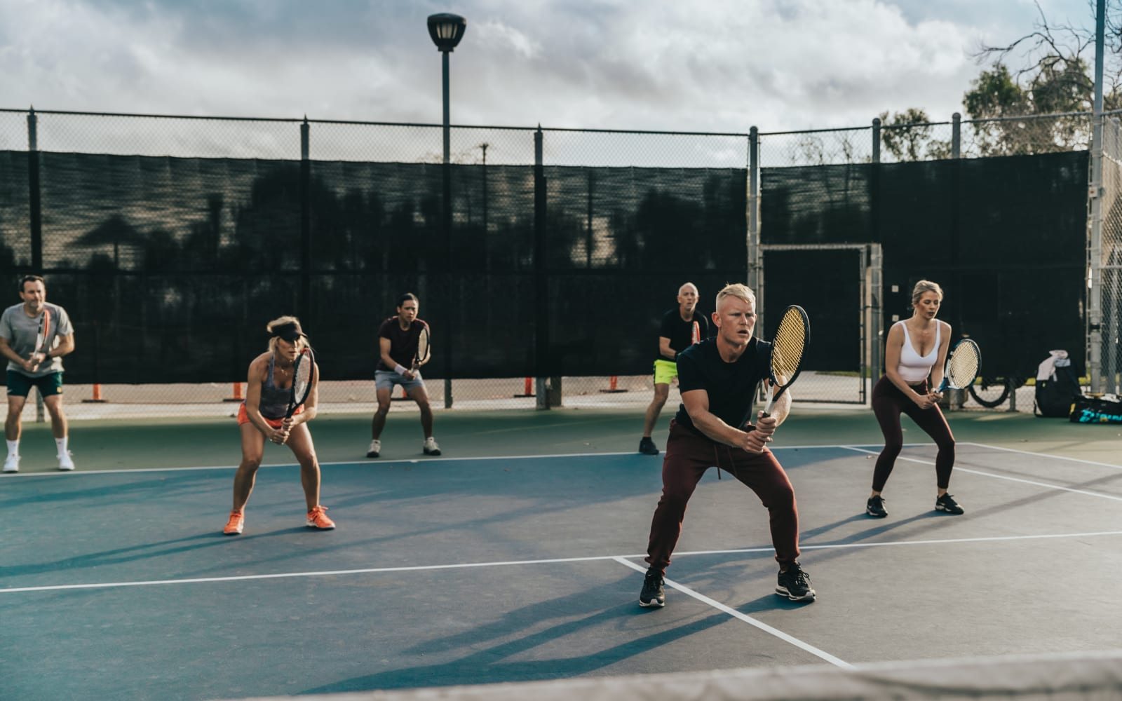 Adults in ready position across a full court under the lights