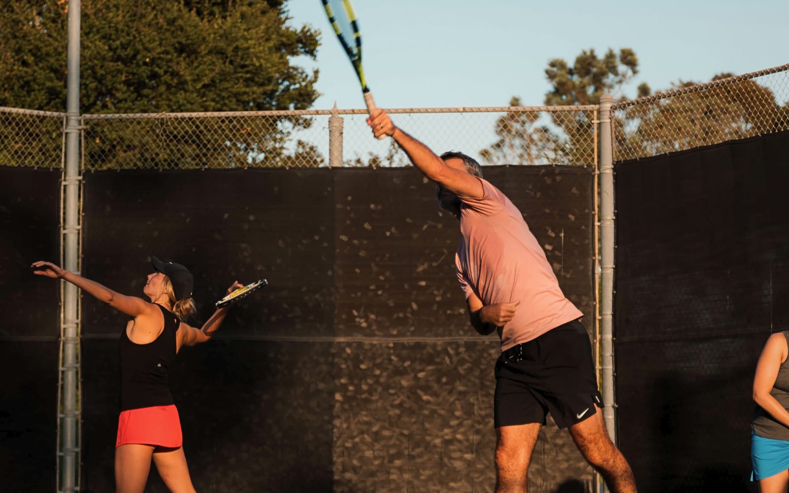Adults reaching up through the serve in evening light