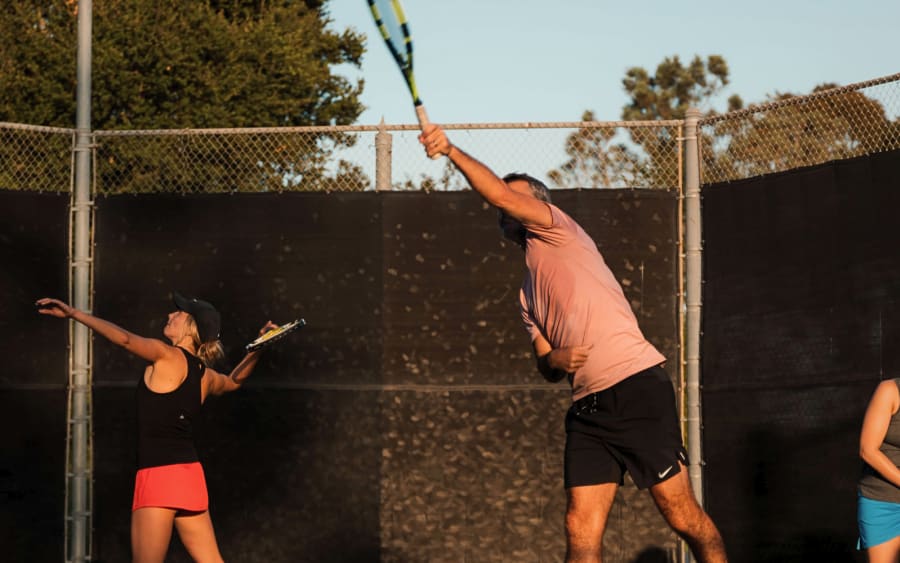 Adults reaching up through the serve in evening light
